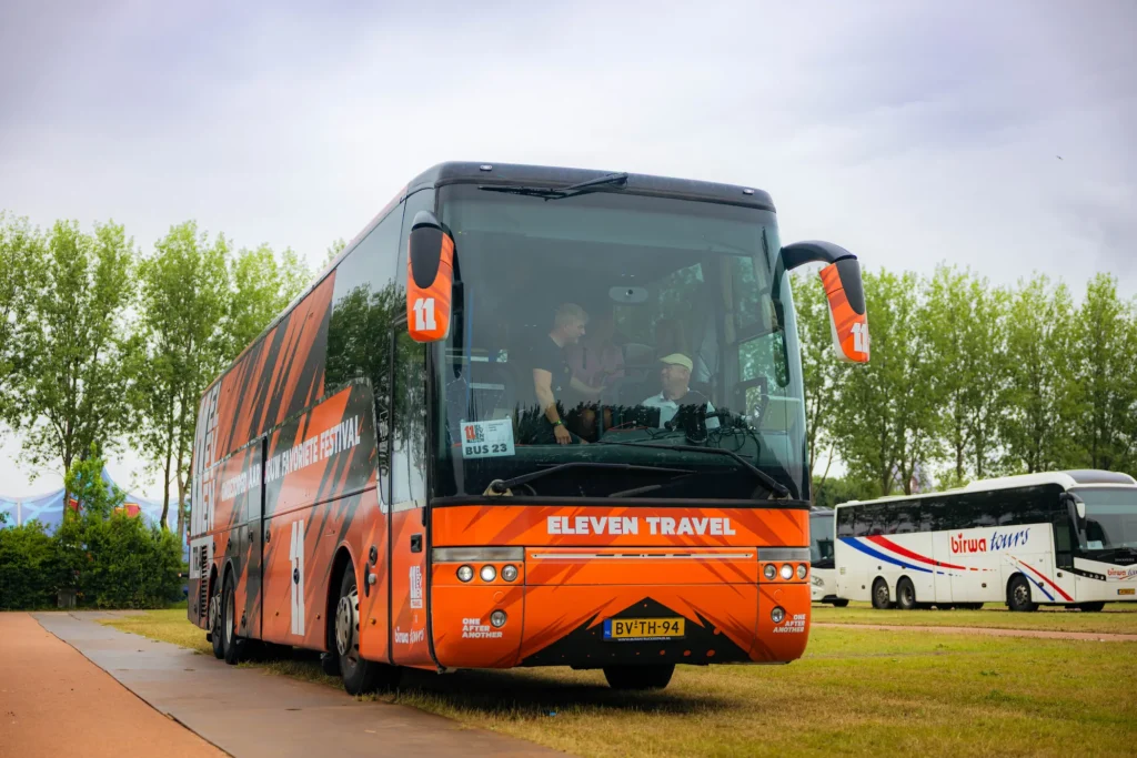 Oranje touringcar van Eleven Travel met de chauffeur achter het stuur