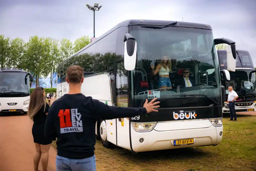 Medewerker van Eleven Travel bij een touringcar van buspartner Beuk op een festivalterrein