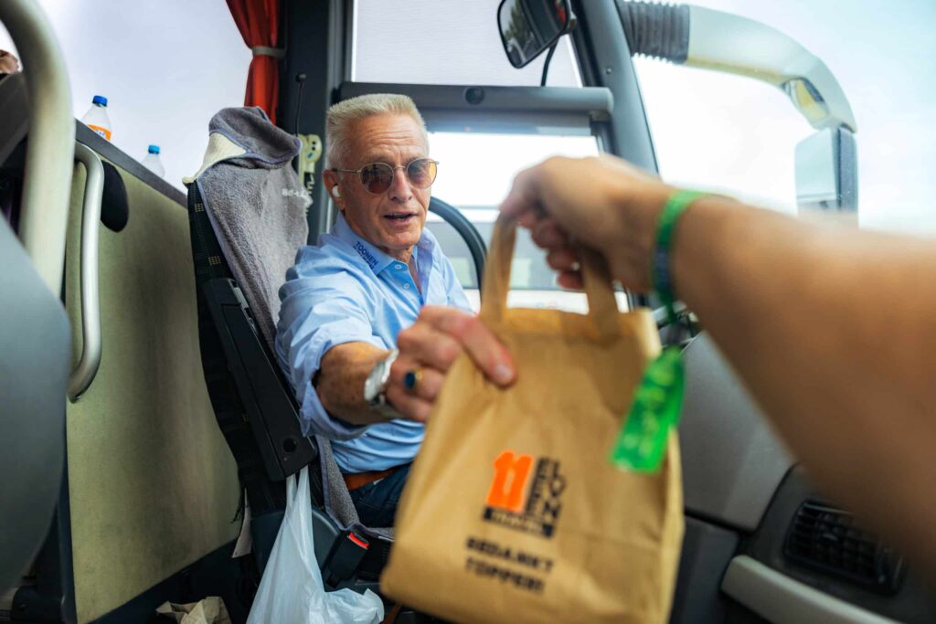 Een chauffeur krijgt in de touringcar een tasje van Eleven Travel aangereikt