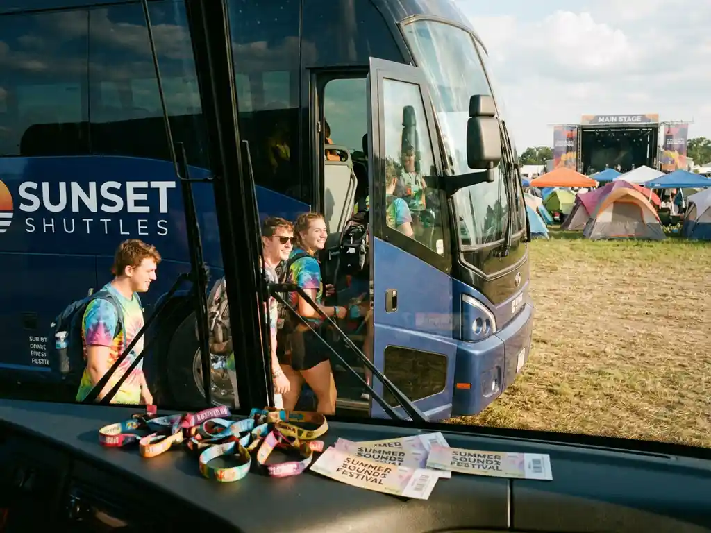 Moderne charterbus bij muziekfestival-ingang met instappende festivalgangers en kleurrijke polsbandjes op dashboard