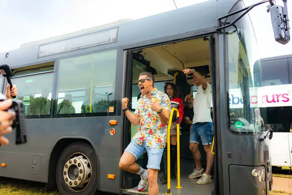 Festivalganger die uit een partybus van eleven travel springt.