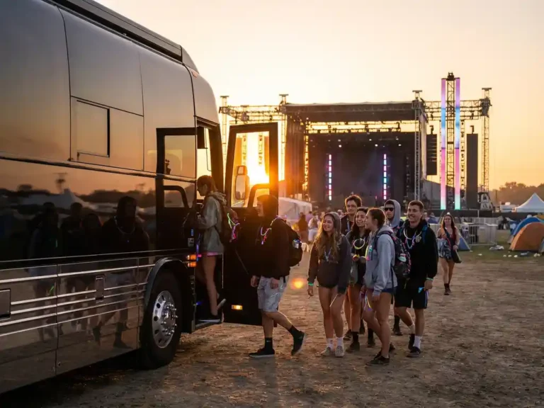 Luxe tourbus met zwarte carrosserie voor elektronisch muziekfestival bij zonsopgang, festivalbezoekers stappen in