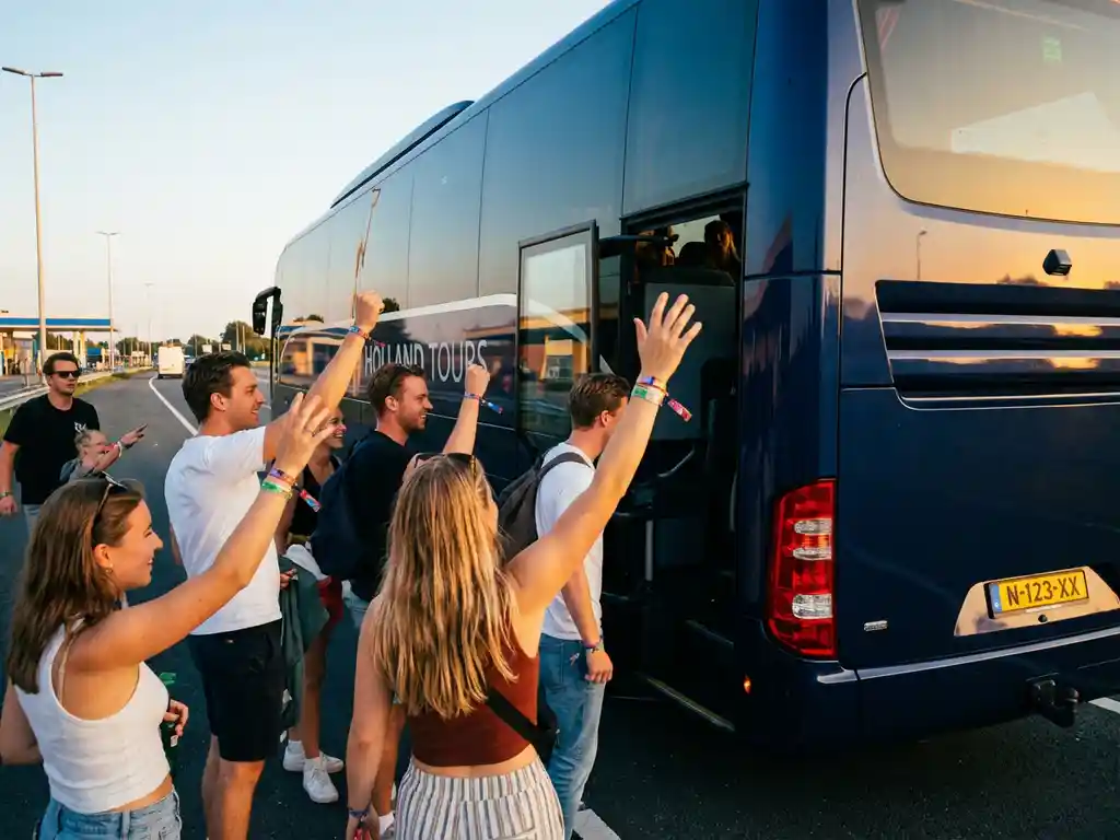 Luxe touringcar bij Nederlandse wegrestaurant met instappende passagiers met Thunderdome festivalpolsbandjes tijdens gouden uur